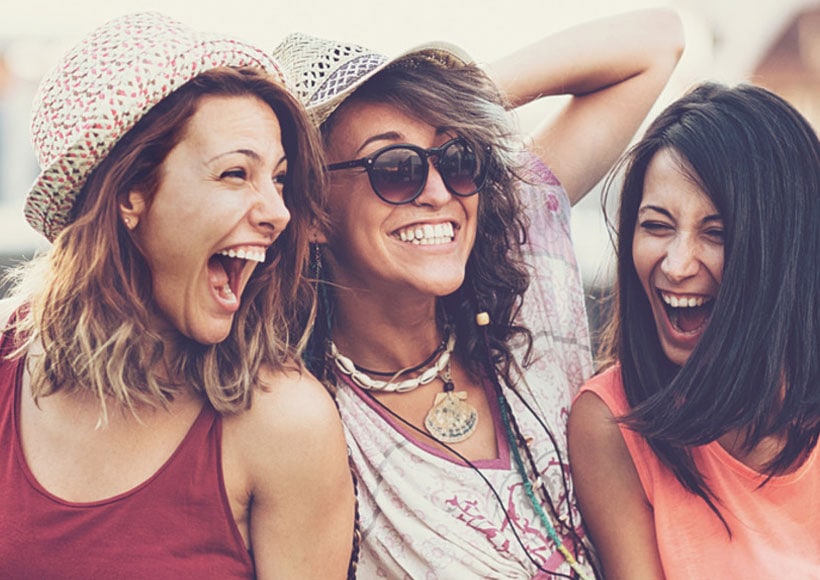 Three friends laughing together outdoors