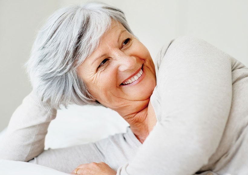 Smiling senior enjoying time with family — confident with new dentures