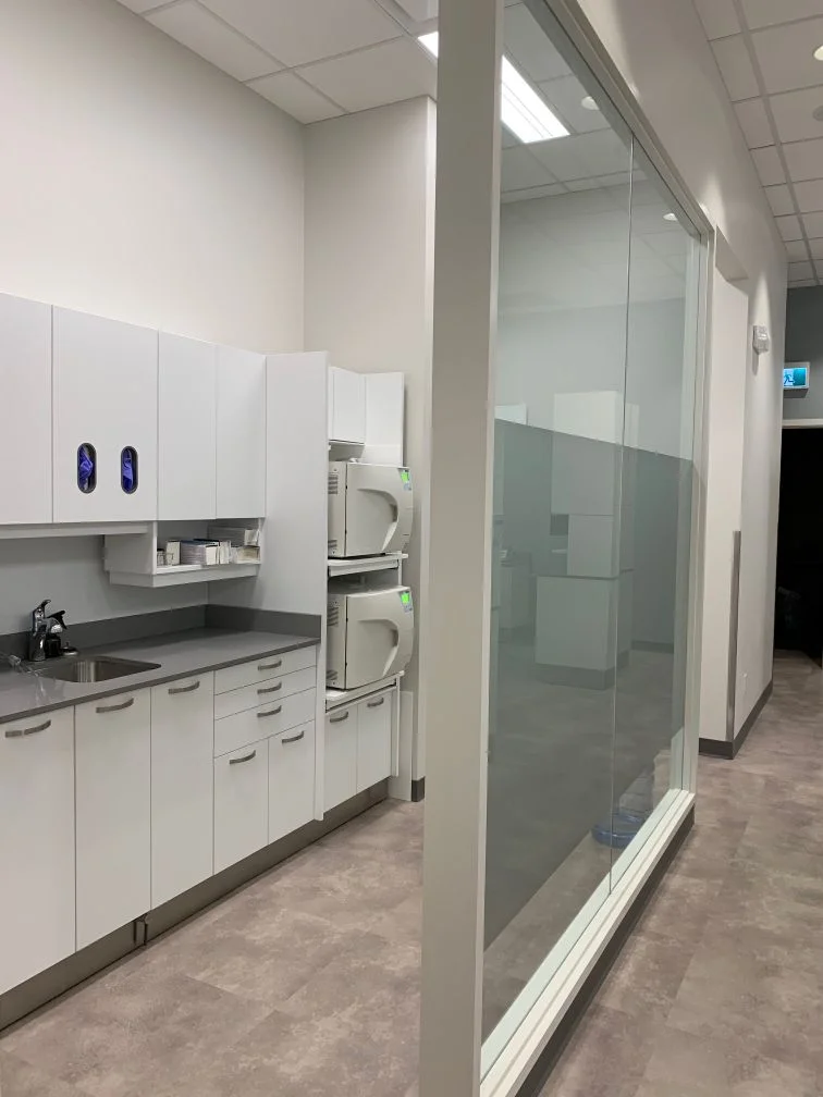 Bright sterilization corridor at Allard Station Dental with autoclaves and a glass partition wall